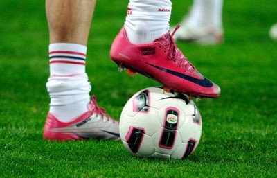 A player wearing soccer cleats with his foot on the ball